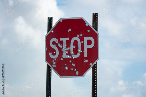 Stop sign against a sky with bullet holes