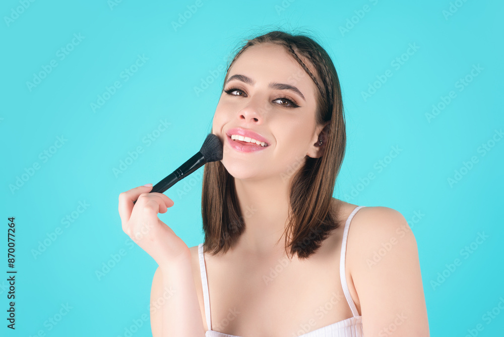 Beautiful young woman applying makeup on studio background. Pretty girl holding makeup brushes and make up on face with cosmetics. Facial beauty. Perfect skin, natural make up. Beautiful young woman applying makeup on studio background. Pretty girl holding makeup brushes and make up on face with cosmetics. Facial beauty. Perfect skin, natural make up.