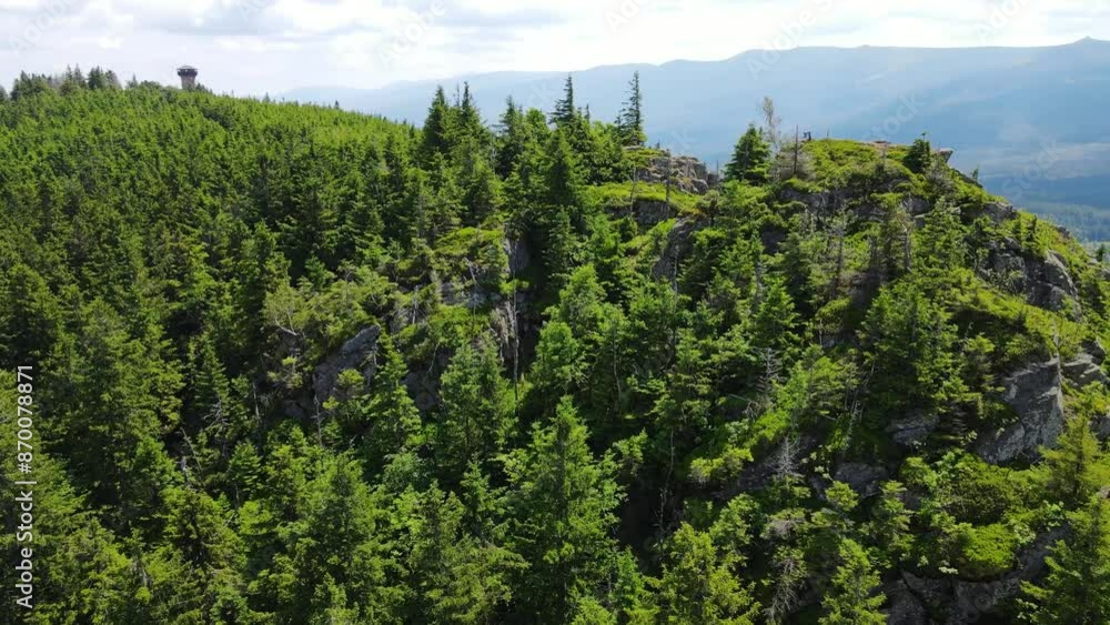 Towering rock formations stand amidst a lush green forest under a clear sky in Saxon Switzerland Mountains range in Germany. Towering rock formations stand amidst a lush green forest under a clear sky in Saxon Switzerland Mountains range in Germany.