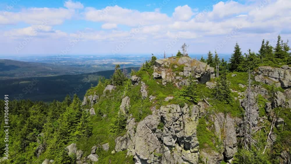 Towering rock formations stand amidst a lush green forest under a clear sky in Saxon Switzerland Mountains range in Germany. Towering rock formations stand amidst a lush green forest under a clear sky in Saxon Switzerland Mountains range in Germany.