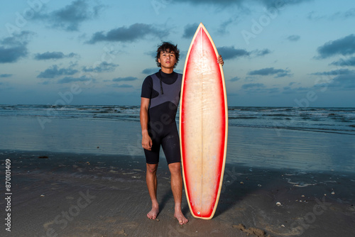 Photography Handsome wet surfer boy standing next to his surfboard after a long day of surfi