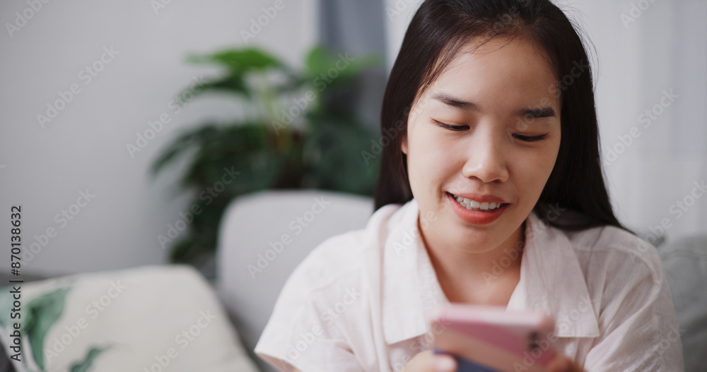 Portrait of Carefree young woman playing social media by smartphone on sofa at home ,Lifestyle with device technology Portrait of Carefree young woman playing social media by smartphone on sofa at home ,Lifestyle with device technology