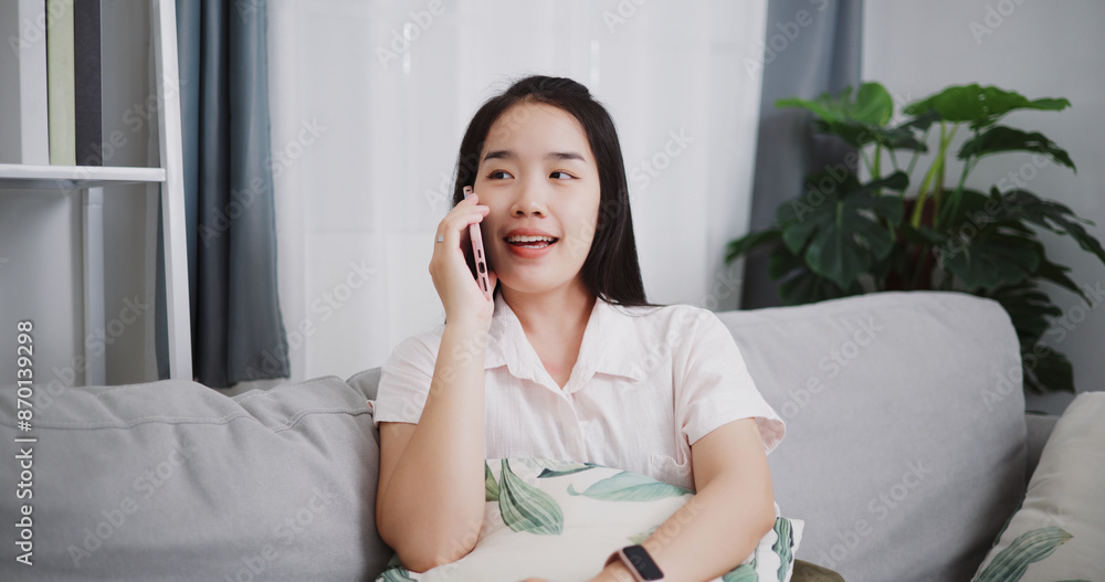 Portrait of Carefree young woman talking with her friend on cell phone on sofa at home ,Lifestyle with device technology, talking and smile with happy Portrait of Carefree young woman talking with her friend on cell phone on sofa at home ,Lifestyle with device technology, talking and smile with happy