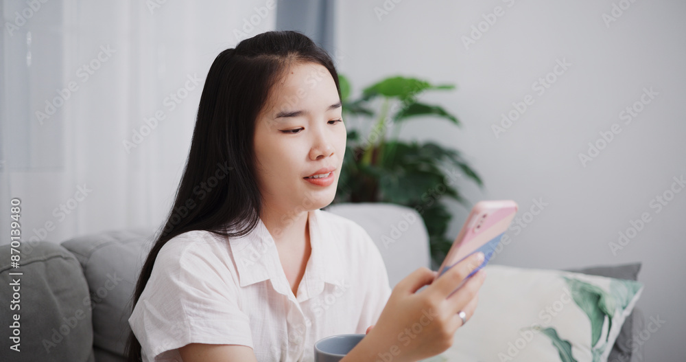 Portrait of Carefree young woman playing social media by smartphone on sofa at home ,Lifestyle with device technology Portrait of Carefree young woman playing social media by smartphone on sofa at home ,Lifestyle with device technology
