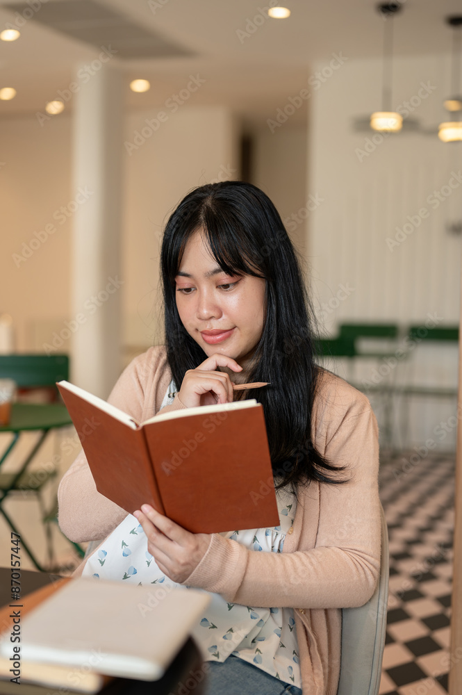 A beautiful, positive Asian woman enjoying reading a book in a beautiful coffee shop. A beautiful, positive Asian woman enjoying reading a book in a beautiful coffee shop.