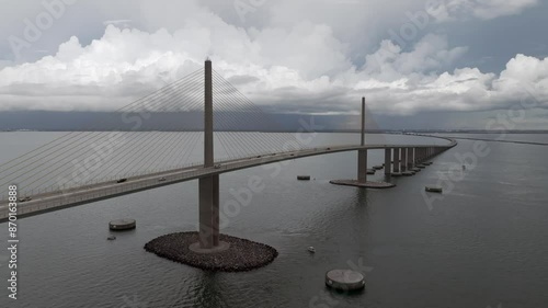 Drone video circling toward the Sunshine Skyway Bridge on a cloudy day with stormy clouds in the distance. Cars are driving on the bridge. 4k 60fps photo