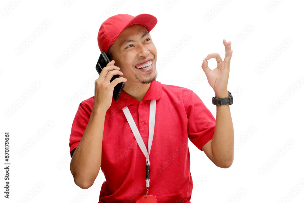 Excited Asian delivery man or courier having an engaging phone call with a customer, showing an OK gesture to indicate agreement or approval. Isolated on a white background. Excited Asian delivery man or courier having an engaging phone call with a customer, showing an OK gesture to indicate agreement or approval. Isolated on a white background.