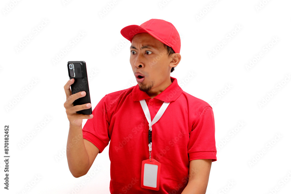 A surprised Asian delivery man or courier reacting to unexpected news on his phone. Isolated on a white background A surprised Asian delivery man or courier reacting to unexpected news on his phone. Isolated on a white background