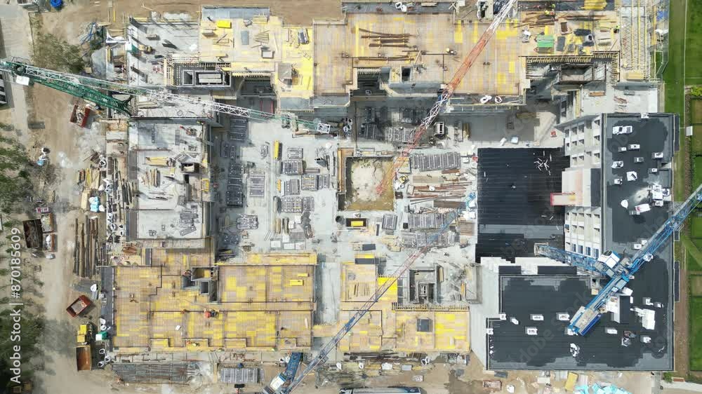 Aerial top down view on the rooftop of an apartment building under construction with tower crane and a lot of workers laying metal rebar Aerial top down view on the rooftop of an apartment building under construction with tower crane and a lot of workers laying metal rebar