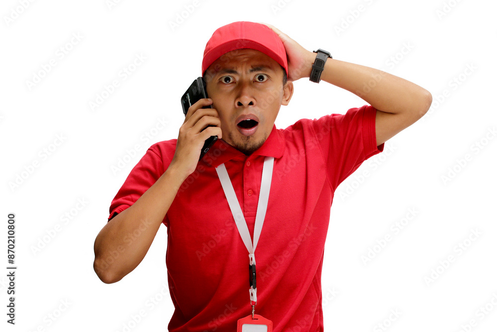 Shocked Asian delivery man or courier receiving unexpected news about a delivery during a phone call. Isolated on a white background Shocked Asian delivery man or courier receiving unexpected news about a delivery during a phone call. Isolated on a white background