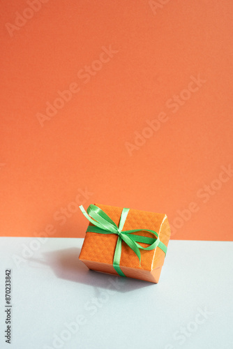 Obraz na płótnie Orange gift box on gray desk. red wall background w salonie