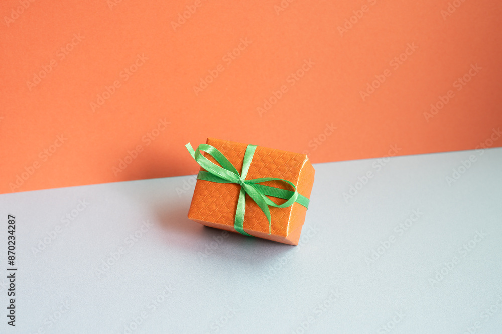 Orange gift box on gray desk. red wall background