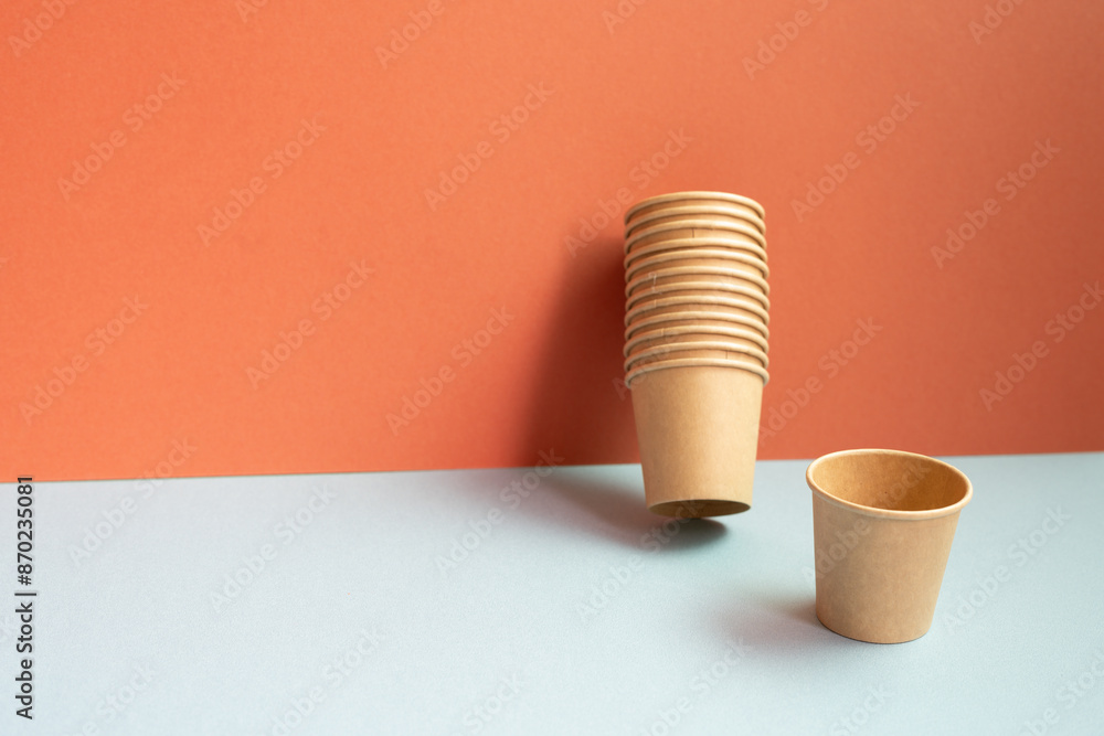 Disposable kraft paper cups on gray table. red wall background