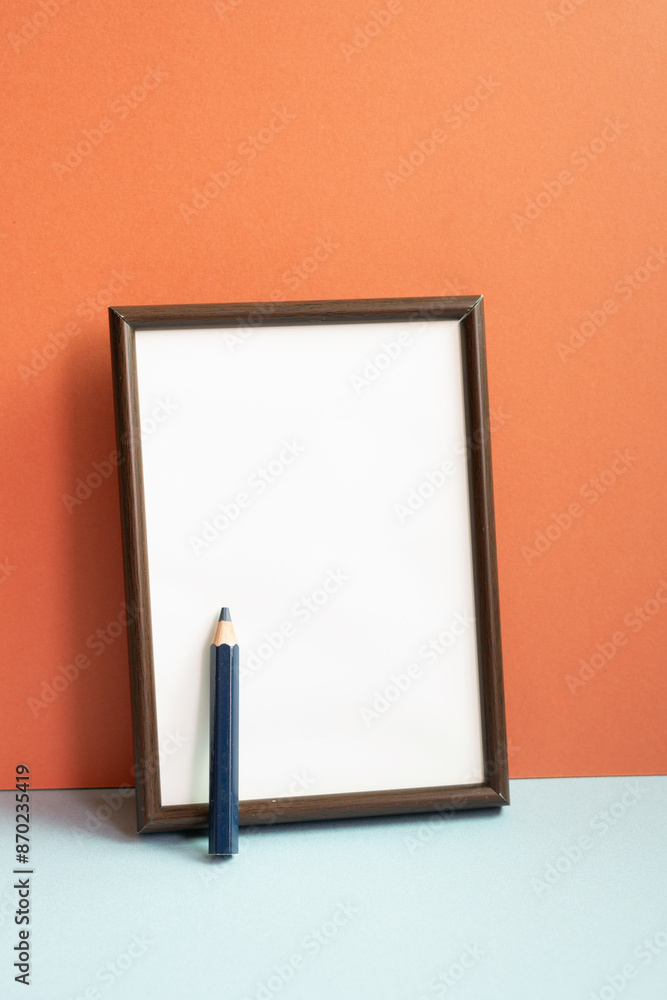 Empty photo frame with colored pencil on gray shelf. red wall background