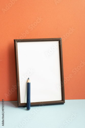 Obraz na płótnie Empty photo frame with colored pencil on gray shelf. red wall background w salonie