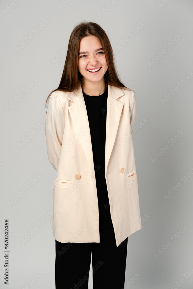Young Woman in White Jacket and Black Pants on Gray Background. Young Woman in White Jacket and Black Pants on Gray Background.