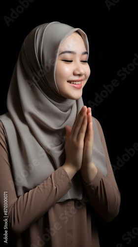 South east asia muslim woman praying to God with hands up on black background