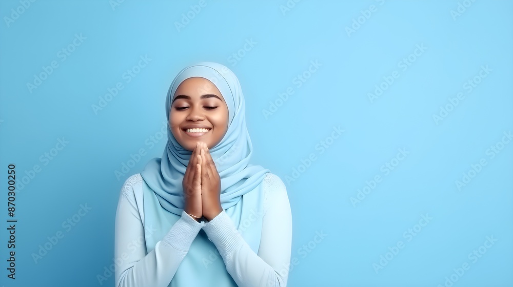 South east asia muslim woman praying to God with hands up on blue background South east asia muslim woman praying to God with hands up on blue background