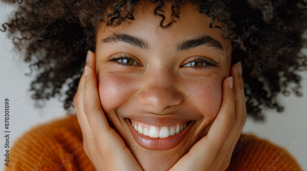 Close-up of a beautiful Black woman with Afro hair smiling and touching her face with her hands Close-up of a beautiful Black woman with Afro hair smiling and touching her face with her hands
