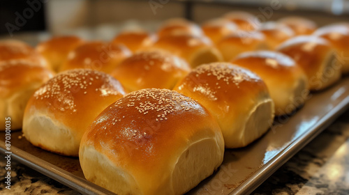 Gourmet dinner rolls with a golden-brown crust, arranged in a neat row on a baking sheet, ready to serve
