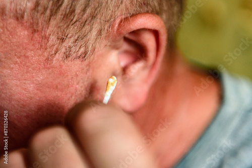 Man cleaning his ears with cotton swabs.