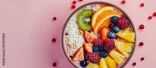 Pineapple fruit smoothie bowl topped with coconut, kiwi, berries, and oranges on a pastel pink background with ample copy space image. © vxnaghiyev