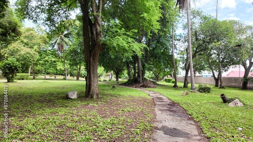 Park with trees, bushes and lawn. A lake, an Asian-style pavilion and hills.