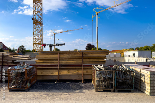 Construction site bustles with stacks of wooden beams and various metal scaffoldingtransformation.