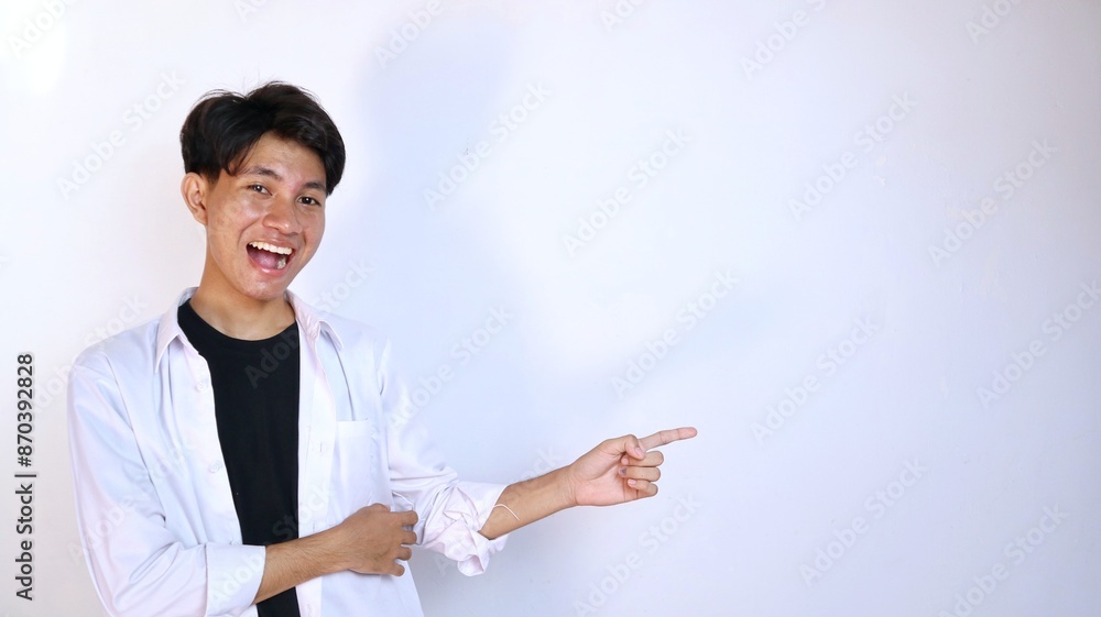 Excited young Asian man gesturing pointing to the side Excited young Asian man gesturing pointing to the side