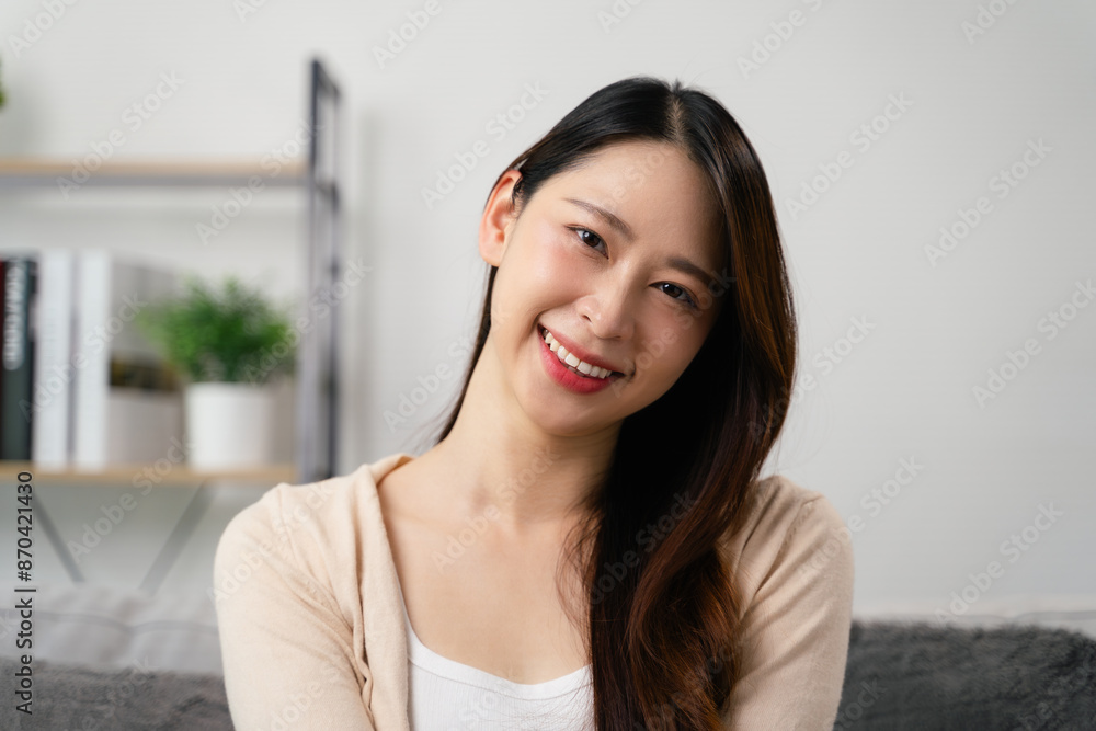 A portrait of beautiful young asian woman is sitting on a couch and smiling. A portrait of beautiful young asian woman is sitting on a couch and smiling.
