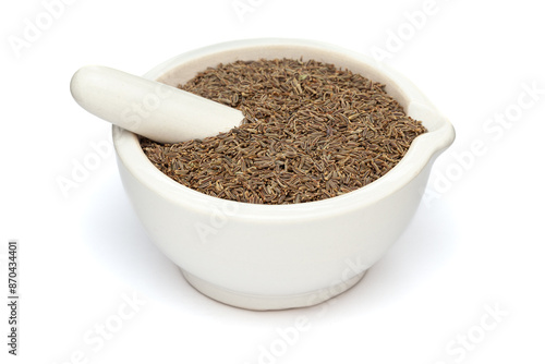 Close-up of Dry Organic Caraway seeds (Carum carvi), in white ceramic mortar and pestle, isolated on a white background. photo