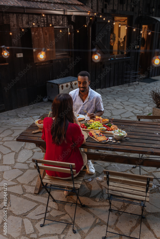 A man enjoying a cozy, private dinner outdoors with a woman A man enjoying a cozy, private dinner outdoors with a woman