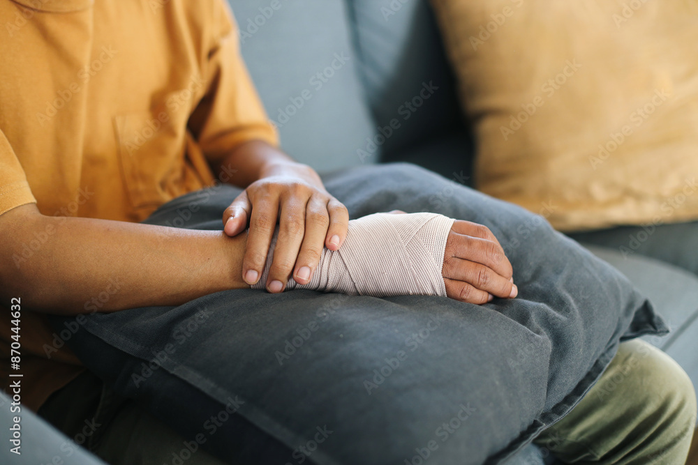 Hand Holding Wrist Elastic Bandage While Sitting On Sofa Hand Holding Wrist Elastic Bandage While Sitting On Sofa