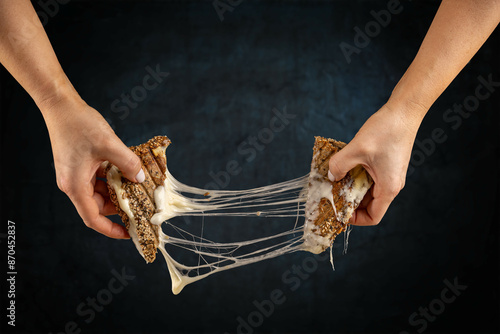 Two hands pulling apart a grilled cheese