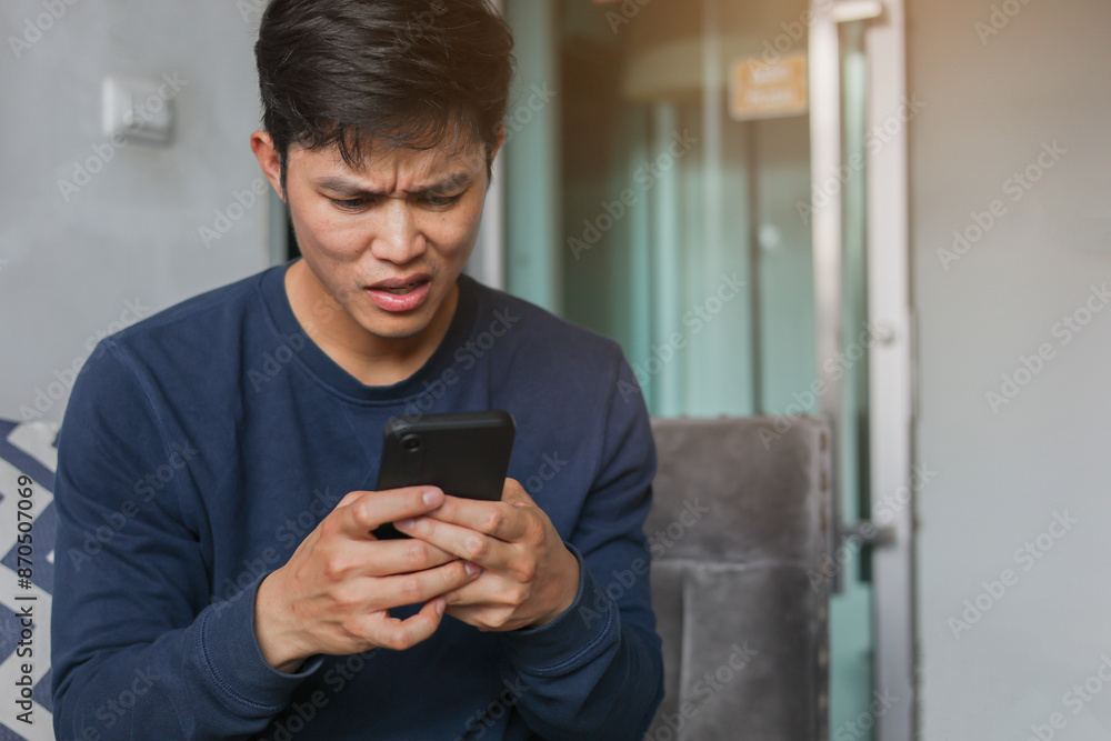 close up young asian man with stress emotion on face with during hold smartphone to reading about bad comment on social media application or read news and rumor in home for people lifestyle concept close up young asian man with stress emotion on face with during hold smartphone to reading about bad comment on social media application or read news and rumor in home for people lifestyle concept