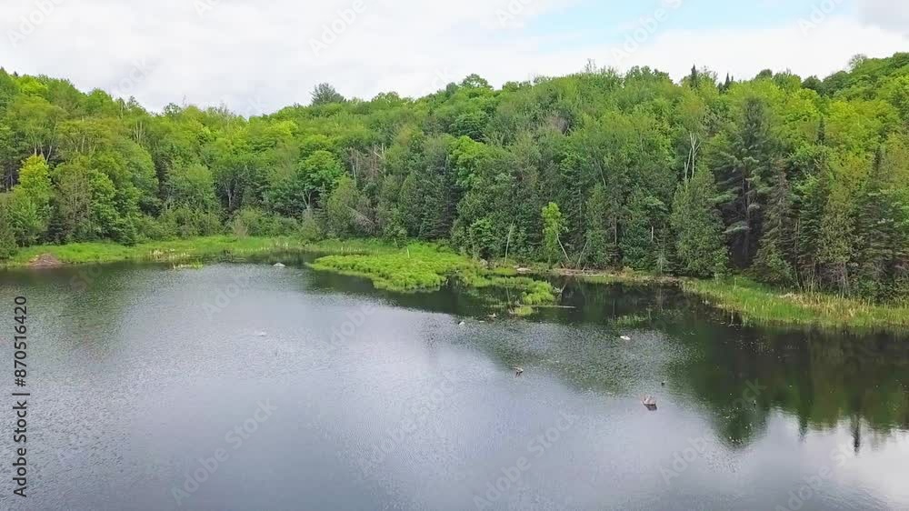 Drone view in mid-air moving slowly forward over a quiet lake showing the reflection of the beautiful sky in the water on a beautiful summer day