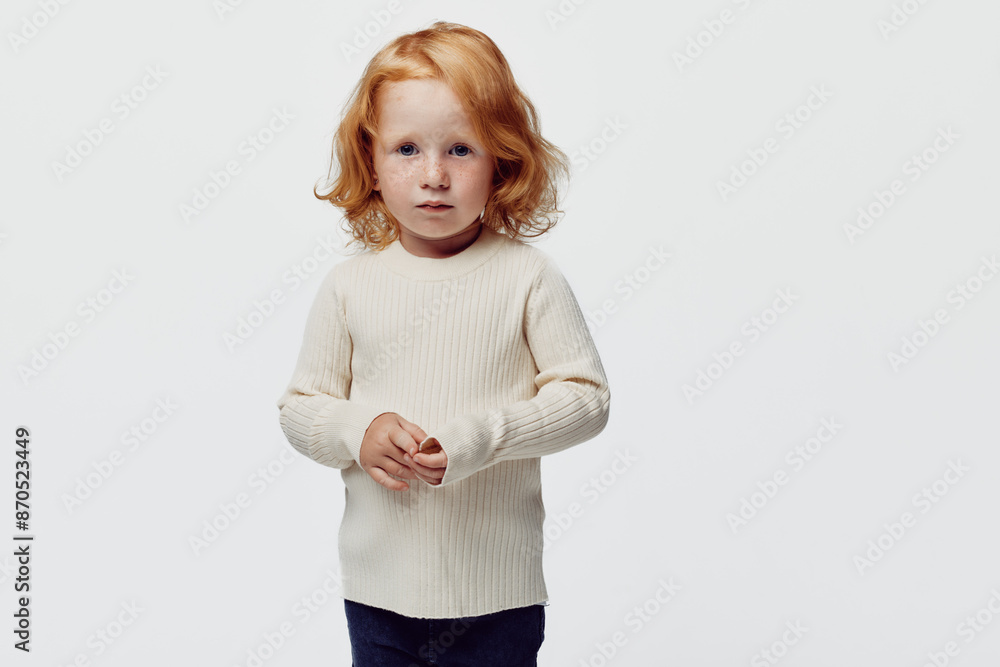 Redhaired girl in white sweater and blue jeans standing in front of white background, fashion and beauty concept Redhaired girl in white sweater and blue jeans standing in front of white background, fashion and beauty concept