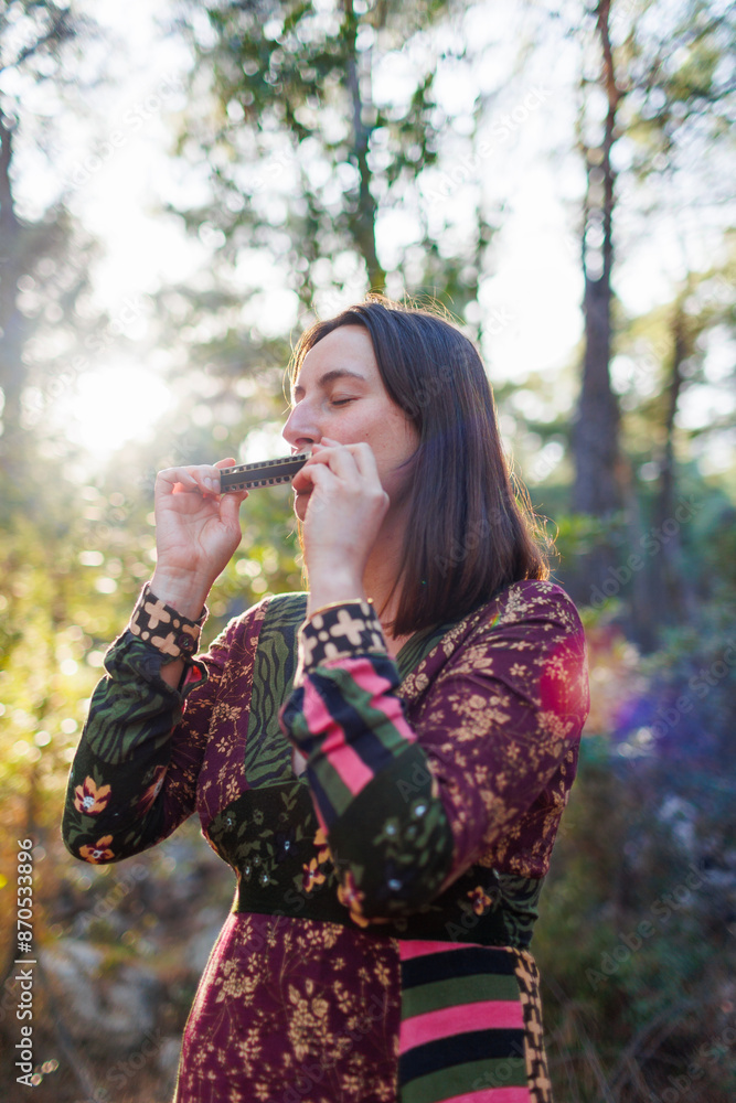 young girl plays the harmonica in the forest. girl enjoys playing a musical instrument in the forest. young girl plays the harmonica in the forest. girl enjoys playing a musical instrument in the forest.