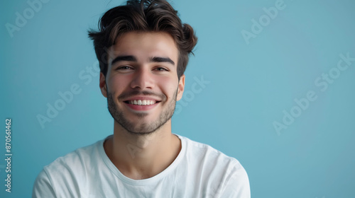 A millennial man in a casual shirt, smiling confidently at the camera against a solid light blue background