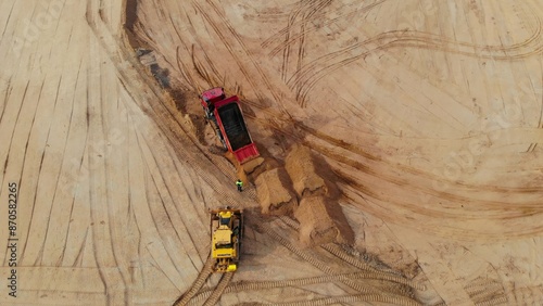 Drone view of bulldozers and dump trucks burying nuclear waste at remote site. Heavy machinery handles dangerous nuclear waste disposal, raising environmental and safety concerns.
