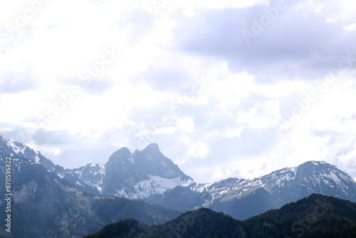 The tops of the mountains with snow visible against the background of a cloudy sky