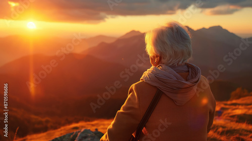 A solitary figure gazes at the breathtaking sunset over a mountain range.  Golden light bathes the landscape.  Tranquil and serene. © Quality Photos