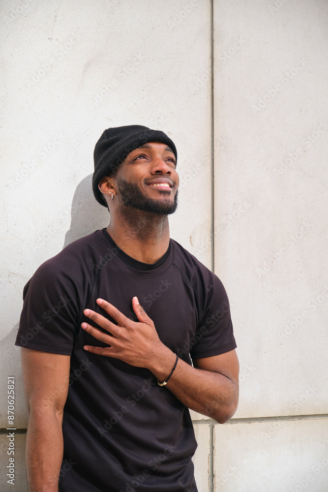 Young urban man is feeling grateful and hopeful while standing against a wall