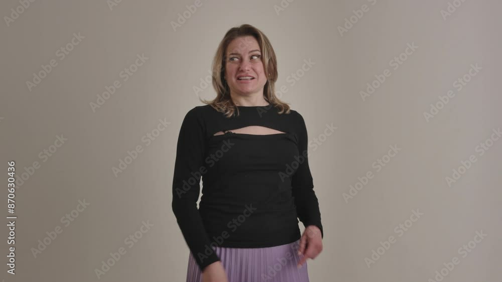A stylish woman in a black sweater and purple skirt is happily pointing sideways with a smile A stylish woman in a black sweater and purple skirt is happily pointing sideways with a smile
