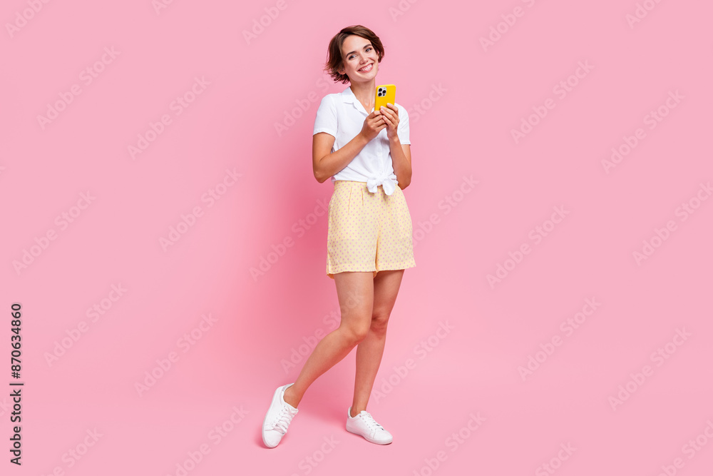 Full body size photo of cheerful attractive young lady post her new video blog account using smartphone isolated on pink color background Full body size photo of cheerful attractive young lady post her new video blog account using smartphone isolated on pink color background