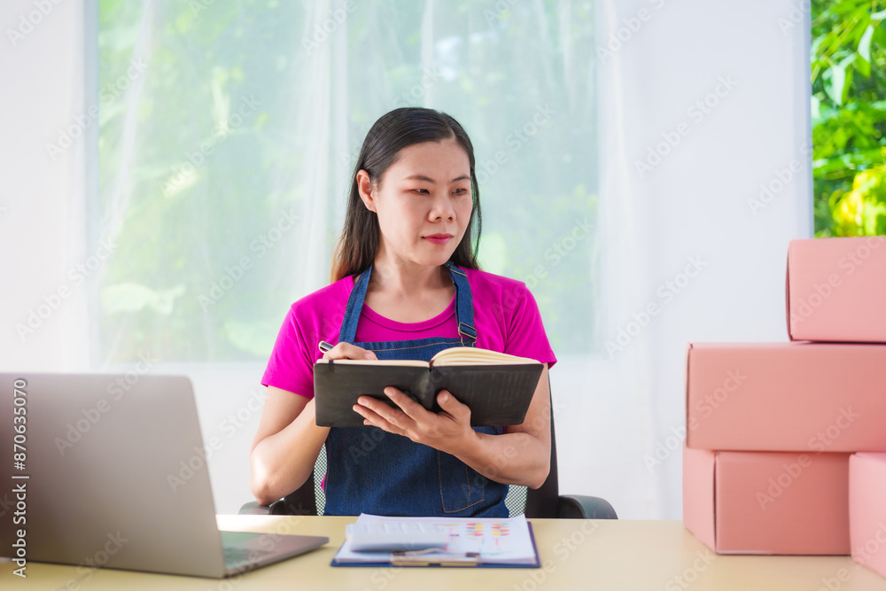 A woman in overalls sells products online, inspects parcels, takes customer orders, works at a desk, and uses pink boxes to pack items ready for shipping to customers. A woman in overalls sells products online, inspects parcels, takes customer orders, works at a desk, and uses pink boxes to pack items ready for shipping to customers.