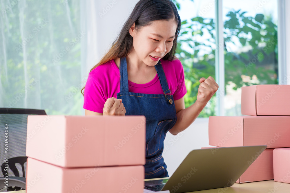 A woman in overalls sells products online, inspects parcels, takes customer orders, works at a desk, and uses pink boxes to pack items ready for shipping to customers. A woman in overalls sells products online, inspects parcels, takes customer orders, works at a desk, and uses pink boxes to pack items ready for shipping to customers.