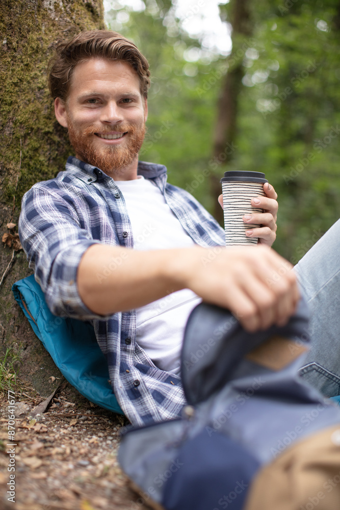 man resting on wooden log in forest drinking hot drink man resting on wooden log in forest drinking hot drink