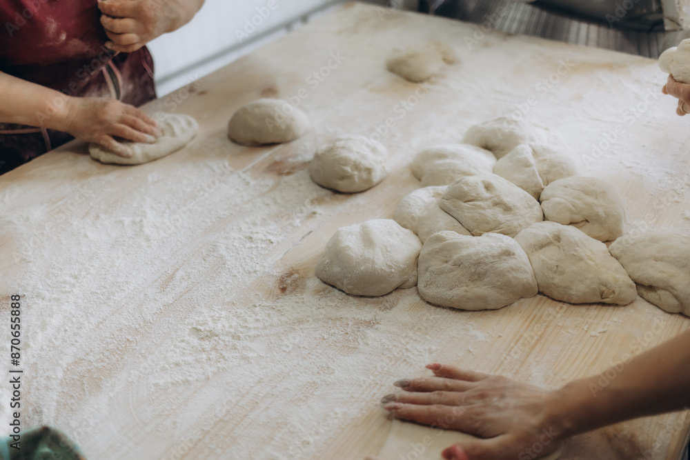 Unrecognizable young man kneading dough on wooden table. Males hands making bread on dark background. Selective focus. Unrecognizable young man kneading dough on wooden table. Males hands making bread on dark background. Selective focus.
