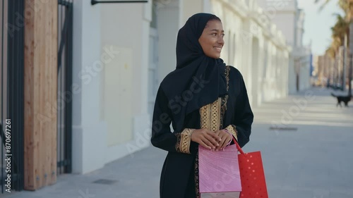 Cinematic image of a beautiful woman from Dubai wearing black abaya dress and walking in the city center and doing shopping.